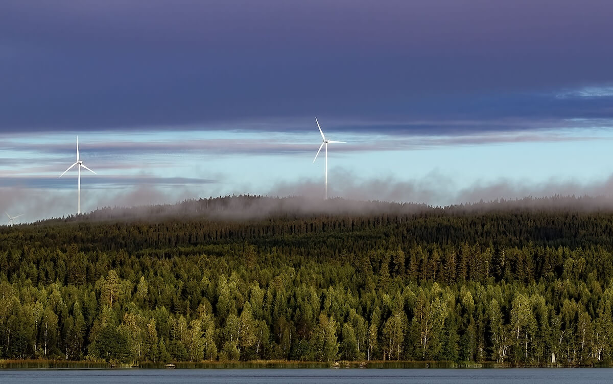 Vindkraftverk över skog och sjö i norra Sverige